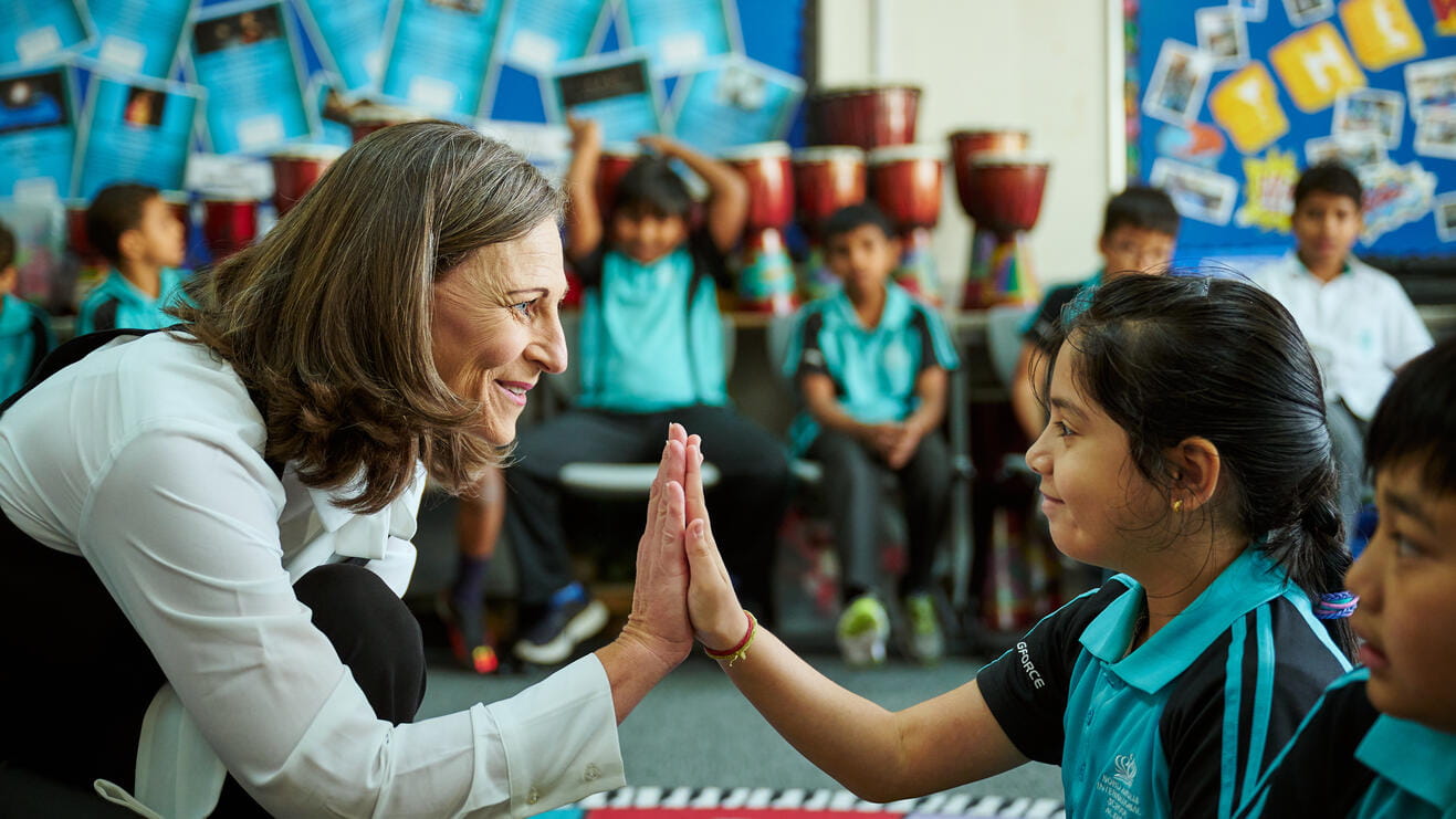 A teacher giving high-five to a primary student