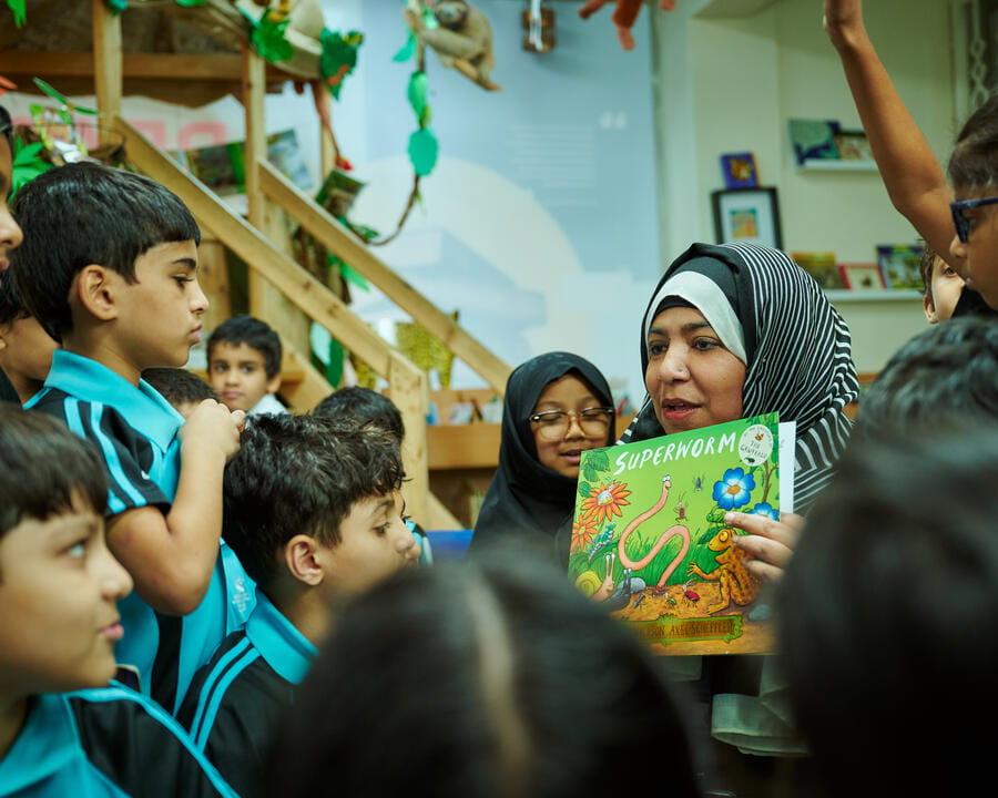 A teacher showing a picture book to primary students