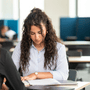 Sixth Form student at NAS Dubai participating in a classroom task, seated at a desk with study materials in a modern learning space.