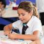 Primary student at NAS Dubai working on a creative drawing activity at a classroom desk, surrounded by stationery and learning materials.