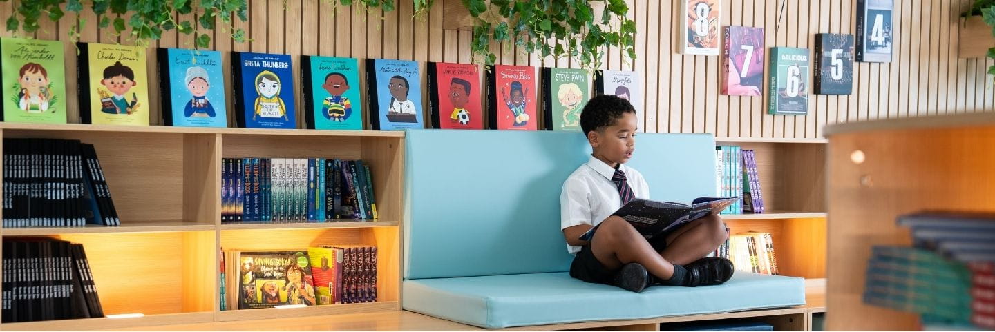 Student in a cozy library setting with colourful sofas and books on display