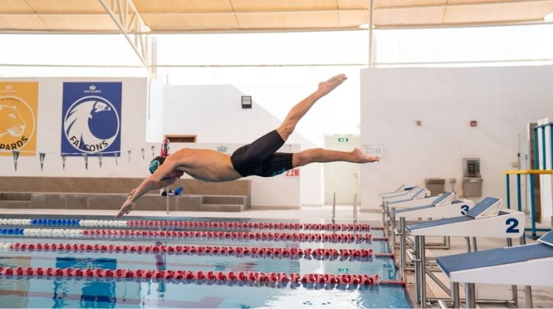 Student diving into a swimming pool during a NAS Dubai training session as part of the school’s sports programme.