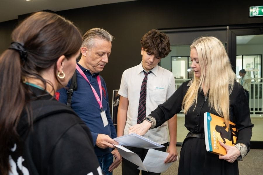 Teacher guiding a family through Sixth Form subject information at the NAS Dubai open evening.