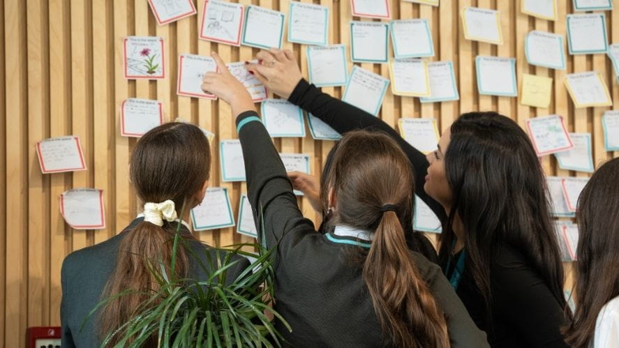 Students placing notes on a wall display during a collaborative learning activity at NAS Dubai international school