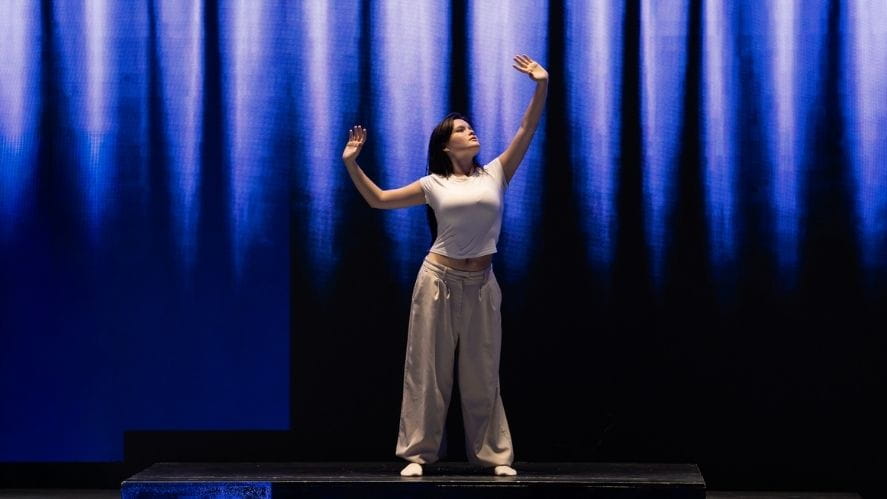 Student presenting IB solo performance on stage, captured mid-expression with dramatic lighting. Student presenting IB solo performance on stage, captured mid-expression with dramatic lighting.