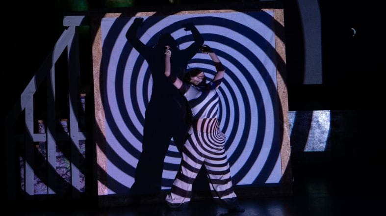 IB performance on stage with spiral background and silhouette displayed dramatically