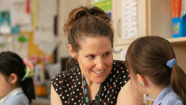 A teacher and young student sat at a table writing