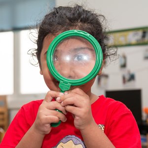 Child with giant green magnifiying glass