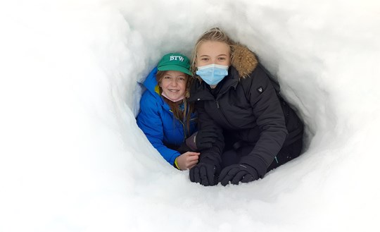 Two students are happy to be safe from the cold in their snowy bunker