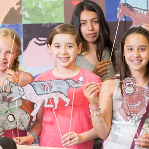 Grade 6 girls smile with puppets they have made in art class
