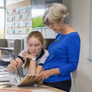 Student looking at book with teacher