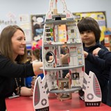 A teacher and students constructing a rocket ship.