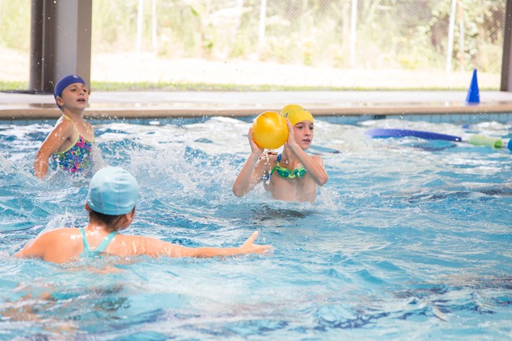 Students playing with a ball in the pool